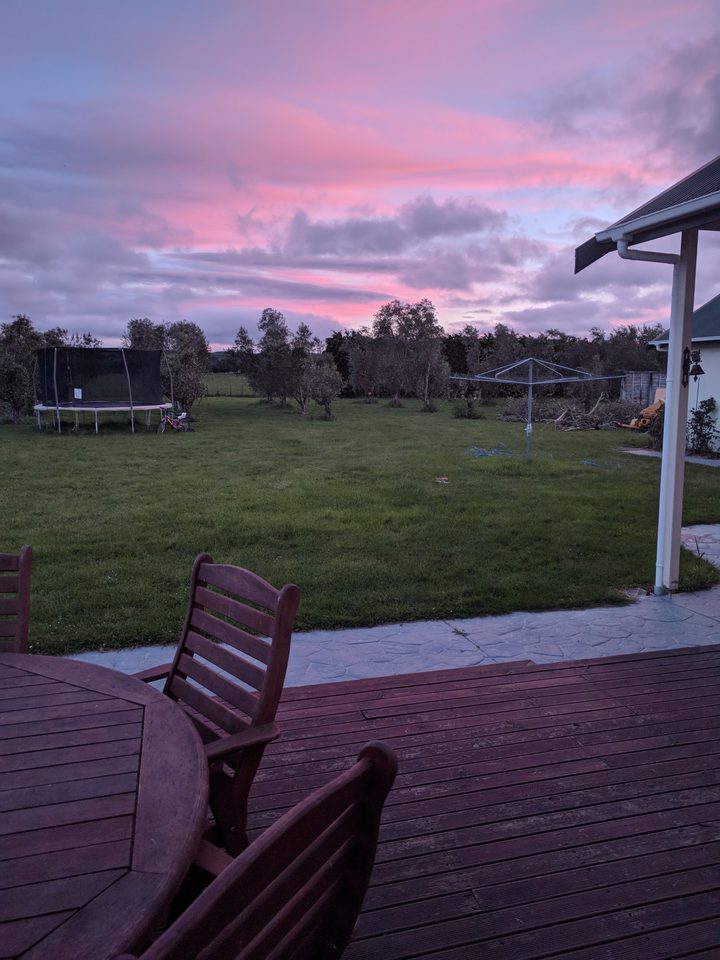 View from the timber deck across the lawn to a pink and mauve sunset sky