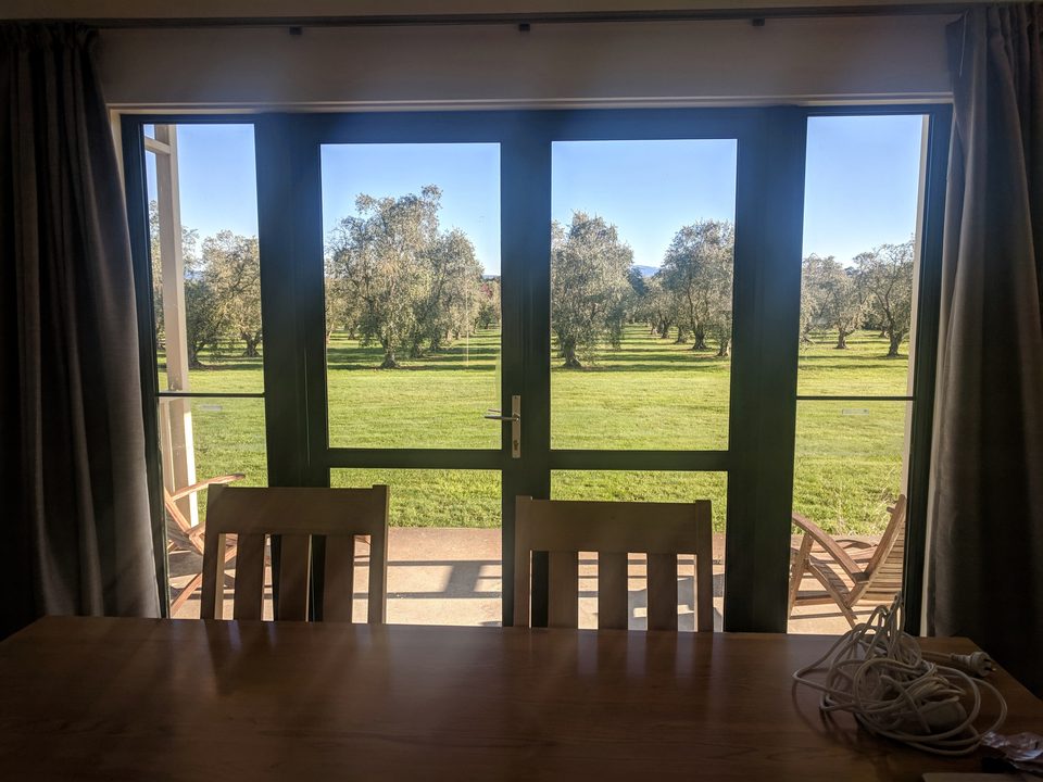 Dining table and chairs looking out through French doors to the olive grove
