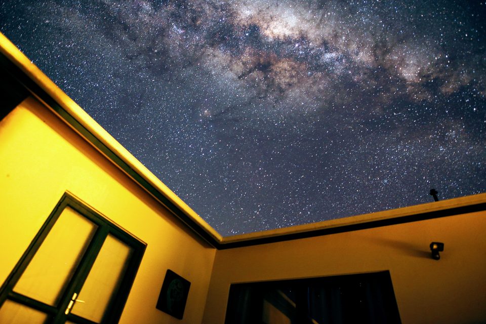 The Milky Way overhead framed by the veranda roof of the house
