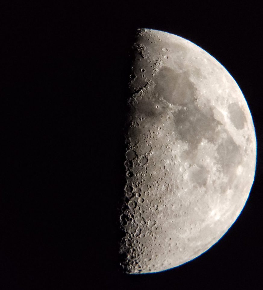 A sharp first-quarter moon showing detailed craters along the terminator