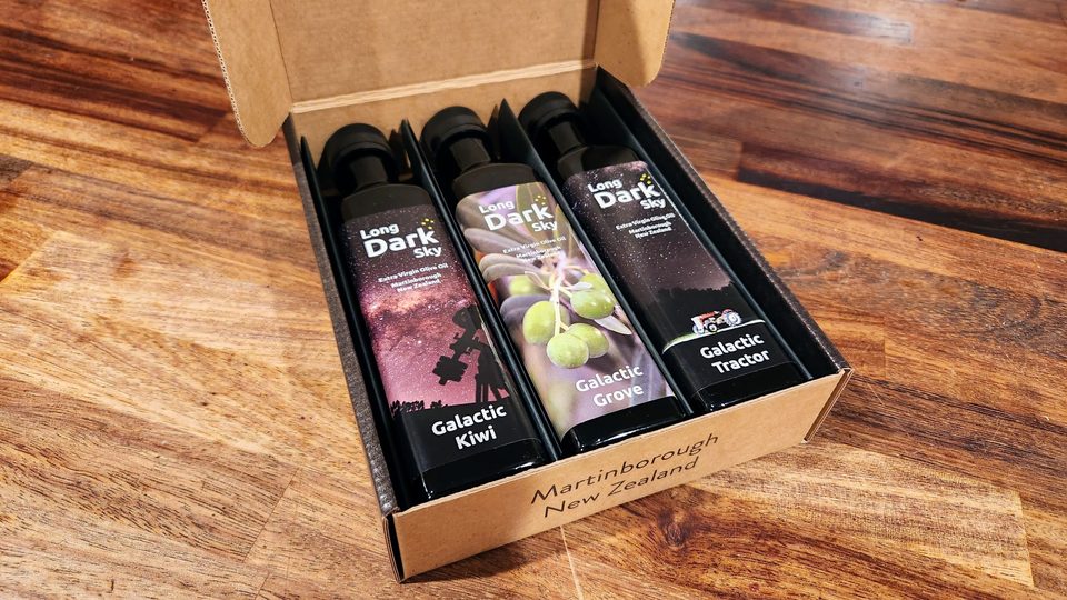 An open kraft gift box holding three bottles of Long Dark Sky olive oil